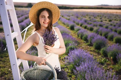 Photo of Beautiful young woman with lavender flowers and wicker basket in field