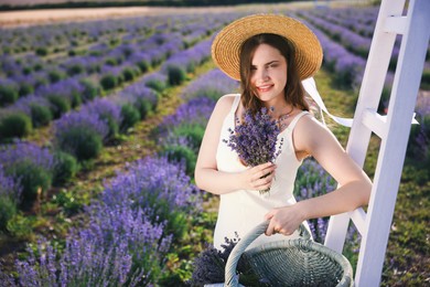 Photo of Beautiful young woman with lavender flowers and wicker basket in field