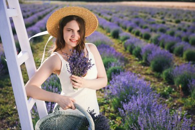Photo of Beautiful young woman with lavender flowers and wicker basket in field