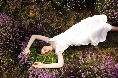 Photo of Beautiful young woman lying among lavender flowers outdoors, top view