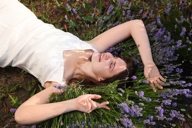 Photo of Beautiful young woman lying among lavender flowers outdoors, above view