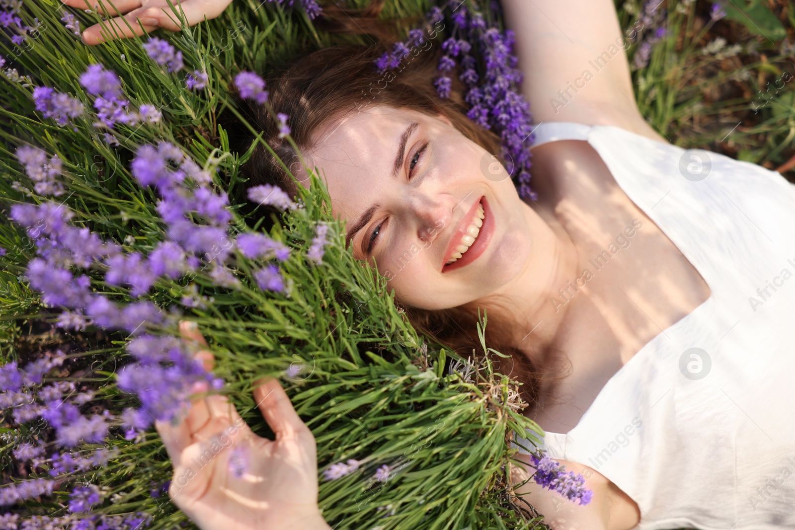 Beautiful young woman lying among lavender flowers outdoors, top view Photo of Beautiful young woman lying among lavender flowers outdoors, top view