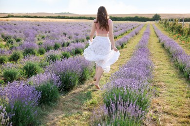 Photo of Woman running through lavender field, back view
