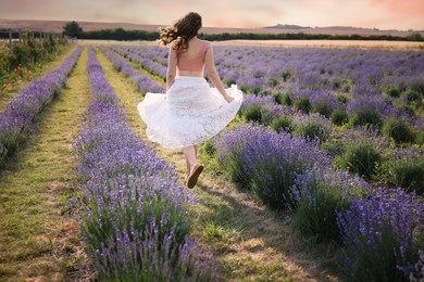 Photo of Woman running through lavender field, back view