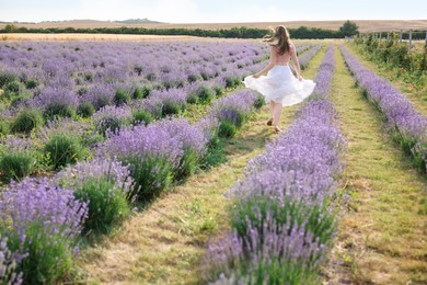 Photo of Woman running through lavender field, back view
