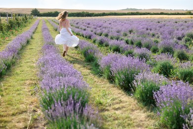 Photo of Woman running through lavender field, back view