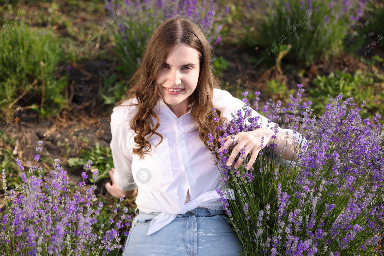 Photo of Beautiful young woman among lavender flowers in field
