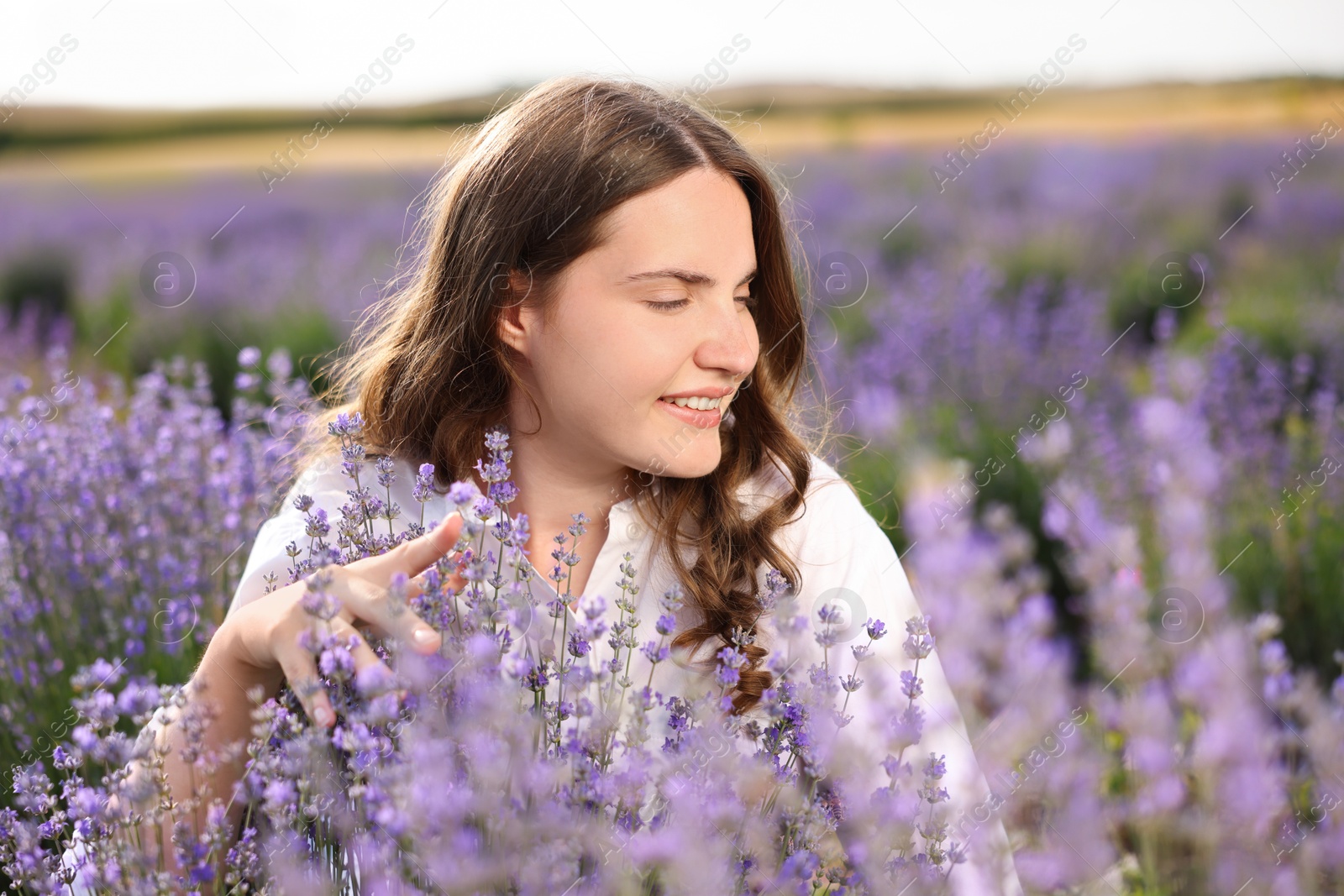 Photo of Beautiful young woman among lavender flowers in field