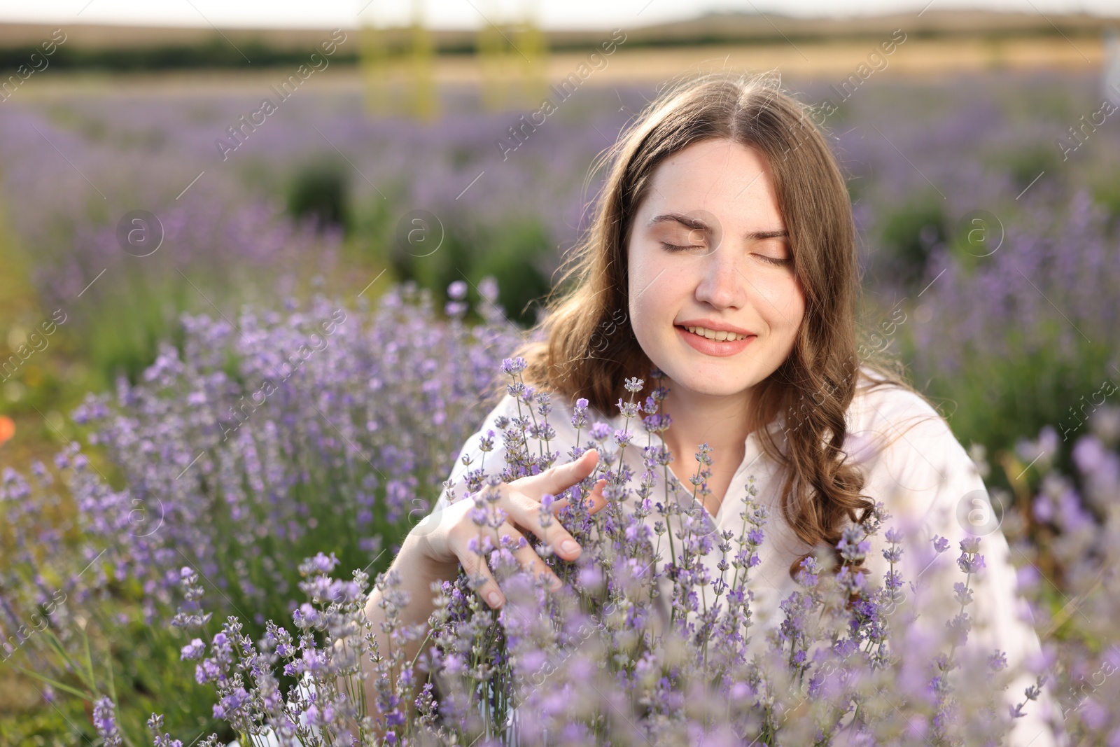 Photo of Beautiful young woman among flowers in lavender field. Space for text
