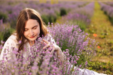 Photo of Beautiful young woman among flowers in lavender field. Space for text