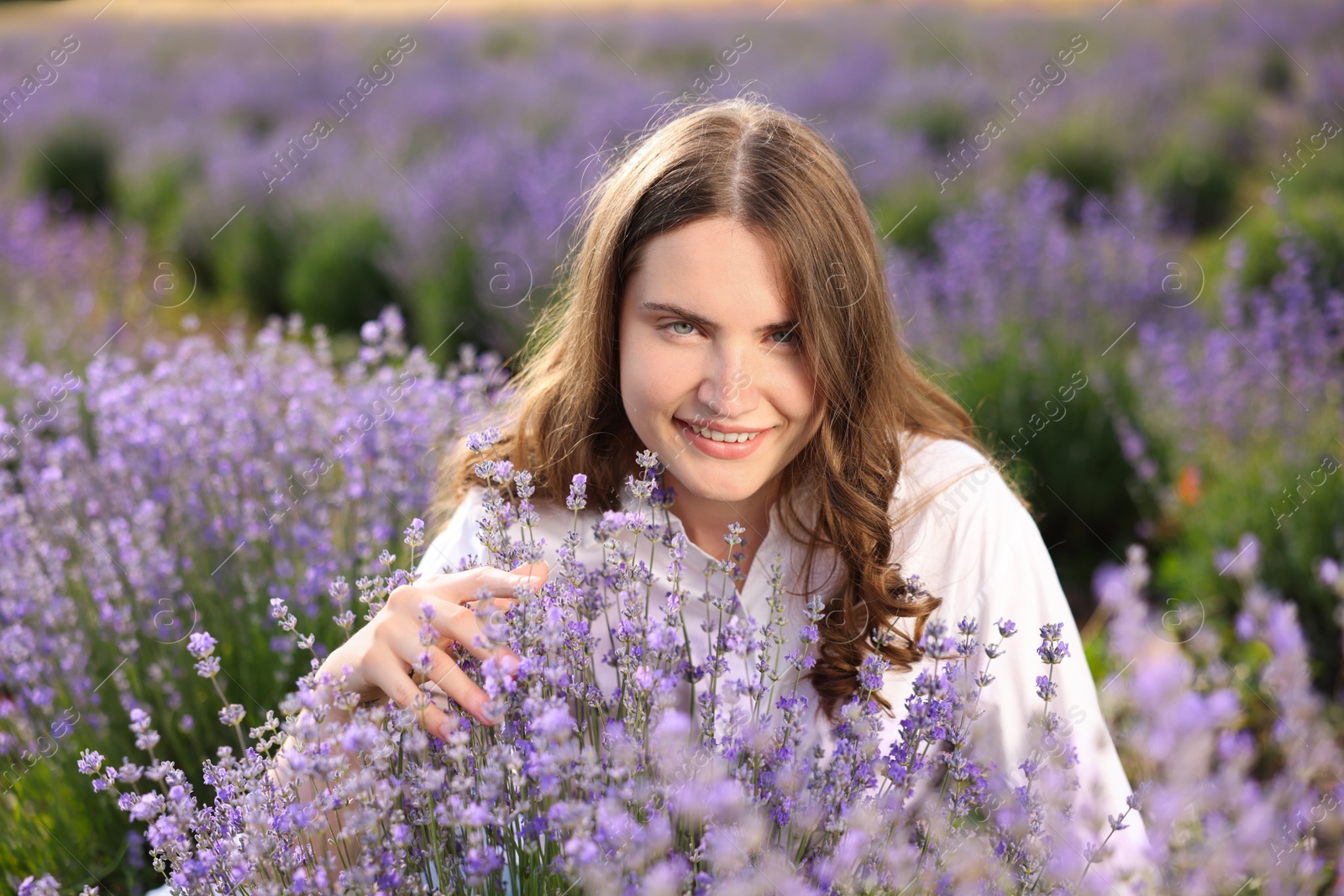 Photo of Beautiful young woman among lavender flowers in field
