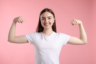 Photo of Strength. Happy woman showing her biceps on pink background