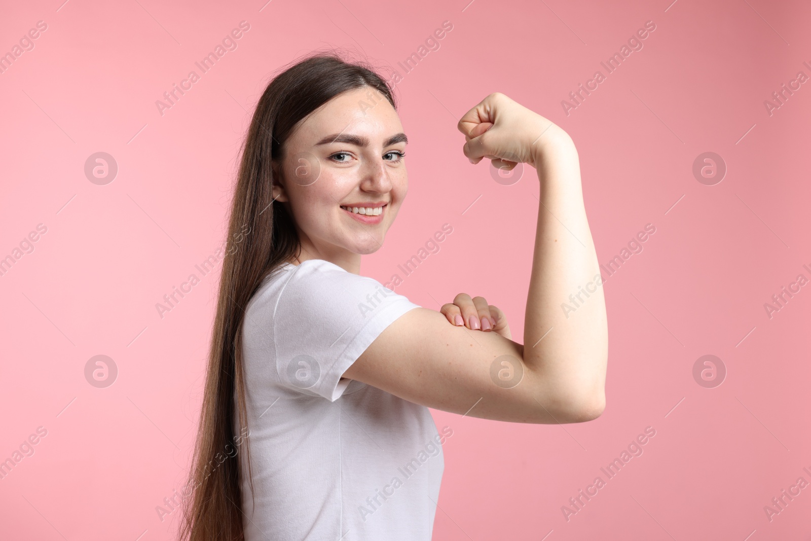 Strength. Happy woman showing her biceps on pink background Photo of Strength. Happy woman showing her biceps on pink background