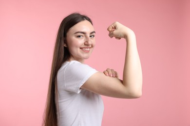Photo of Strength. Happy woman showing her biceps on pink background