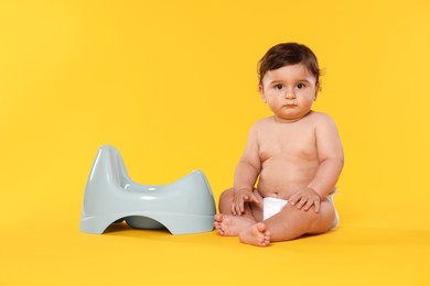 Photo of Cute little baby sitting near potty on orange background