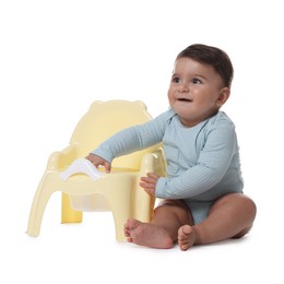 Photo of Cute little baby sitting near potty on white background