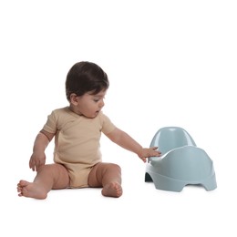 Photo of Cute little baby sitting near potty on white background