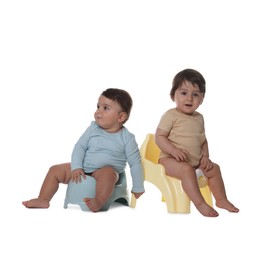 Photo of Cute little babies sitting on potties against white background