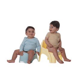 Photo of Cute little babies sitting on potties against white background