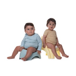 Photo of Cute little babies sitting on potties against white background