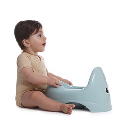 Photo of Cute little baby sitting near potty on white background