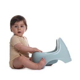 Photo of Cute little baby sitting near potty on white background