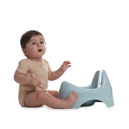 Photo of Cute little baby sitting near potty on white background