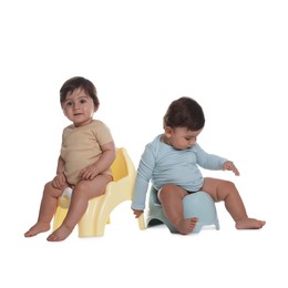 Photo of Cute little babies sitting on potties against white background