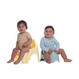 Photo of Cute little babies sitting on potties against white background