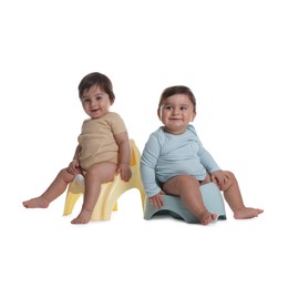 Photo of Cute little babies sitting on potties against white background