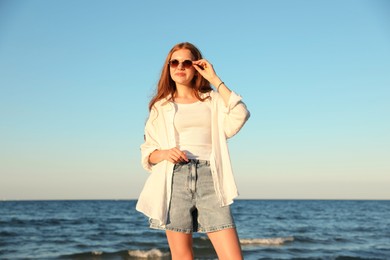 Photo of Beautiful teenage girl in sunglasses near sea