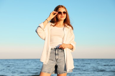 Photo of Beautiful teenage girl in sunglasses near sea