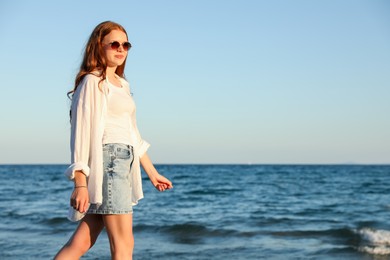 Photo of Beautiful teenage girl walking along seashore outdoors