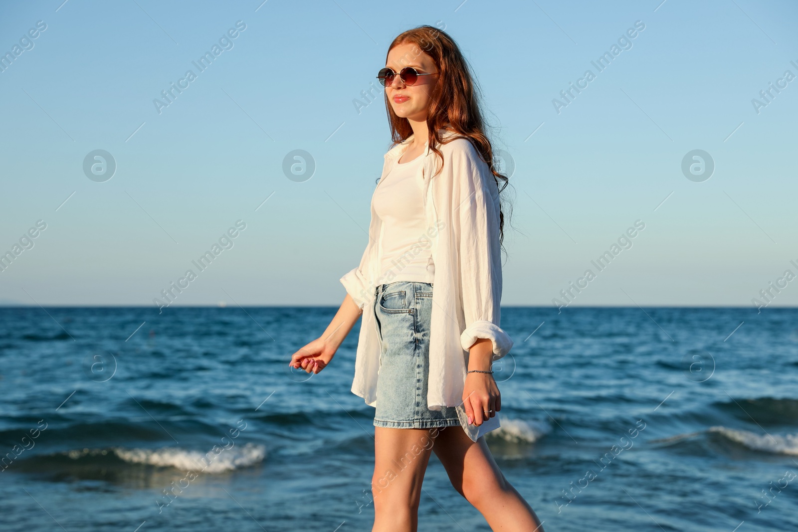 Beautiful teenage girl walking along seashore outdoors Photo of Beautiful teenage girl walking along seashore outdoors