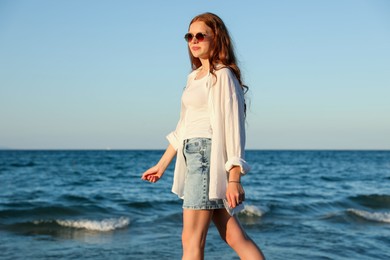 Photo of Beautiful teenage girl walking along seashore outdoors
