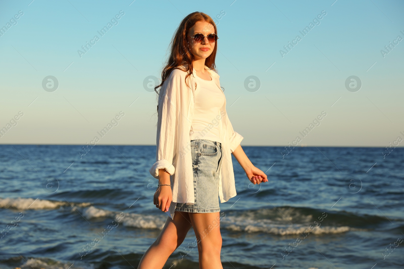 Beautiful teenage girl walking along seashore outdoors Photo of Beautiful teenage girl walking along seashore outdoors