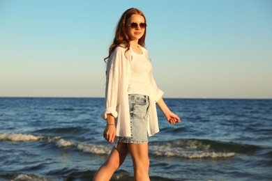 Photo of Beautiful teenage girl walking along seashore outdoors