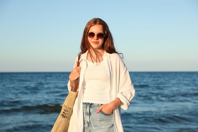 Photo of Beautiful teenage girl with sunglasses and bag near sea