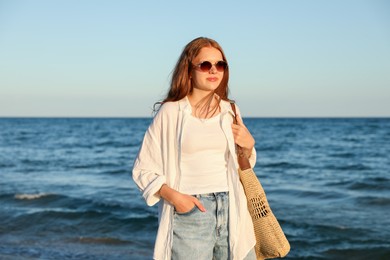 Photo of Beautiful teenage girl with sunglasses and bag near sea