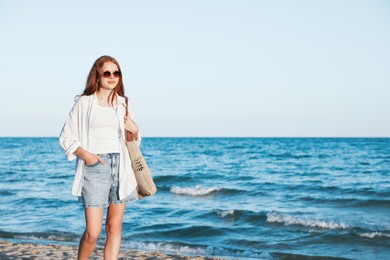 Photo of Beautiful teenage girl walking along seashore outdoors, space for text
