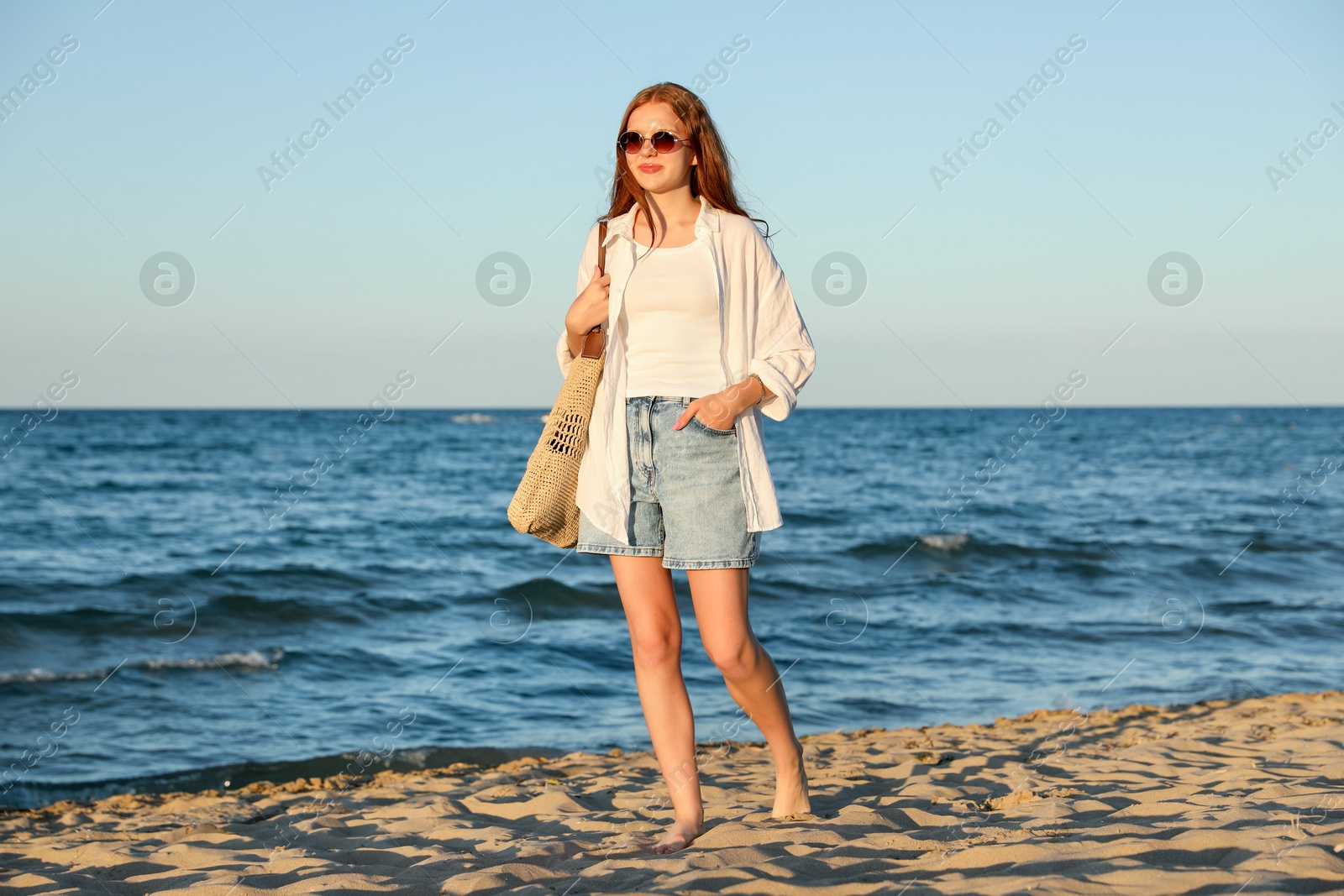 Beautiful teenage girl walking along seashore outdoors Photo of Beautiful teenage girl walking along seashore outdoors