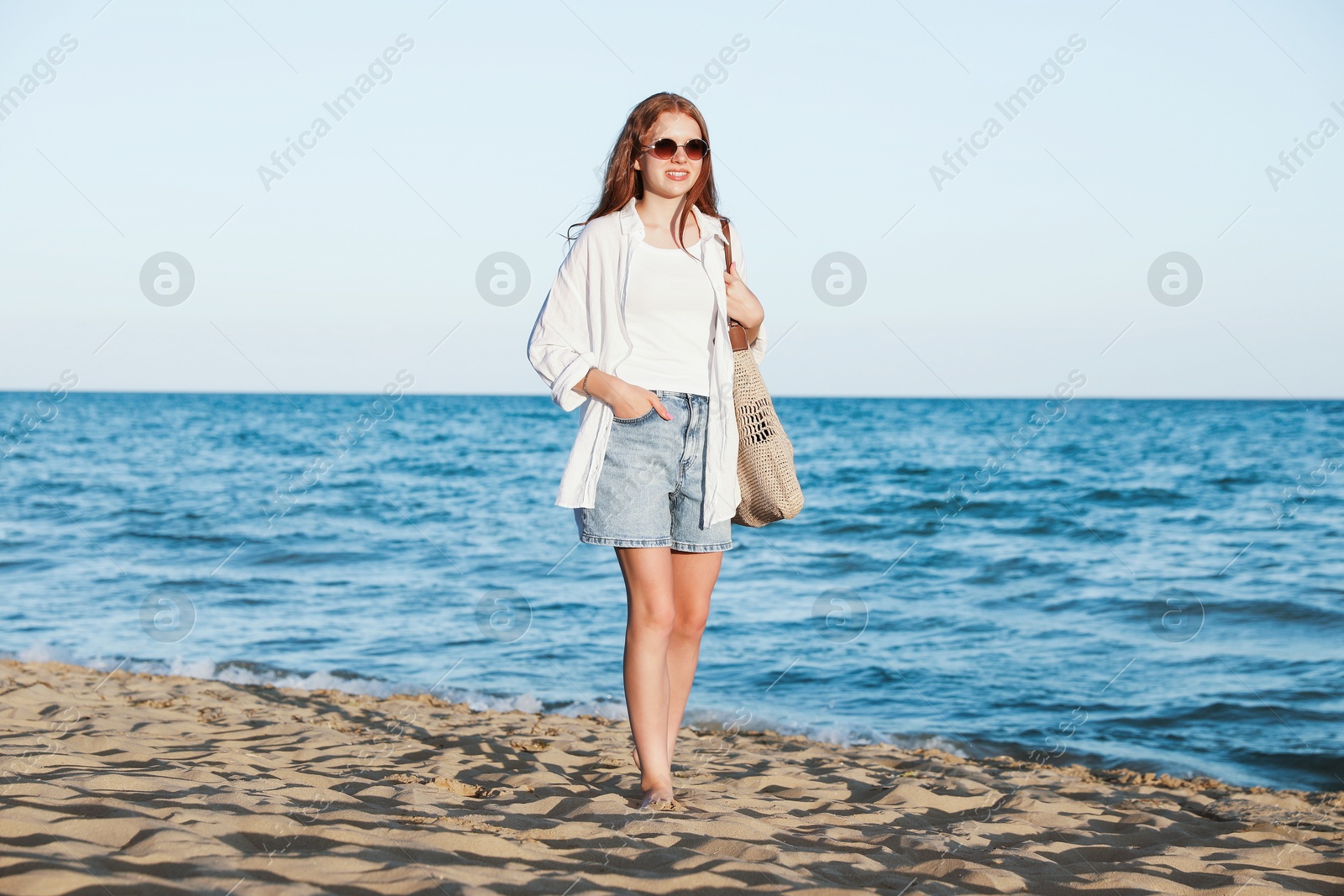 Beautiful teenage girl walking along seashore outdoors Photo of Beautiful teenage girl walking along seashore outdoors