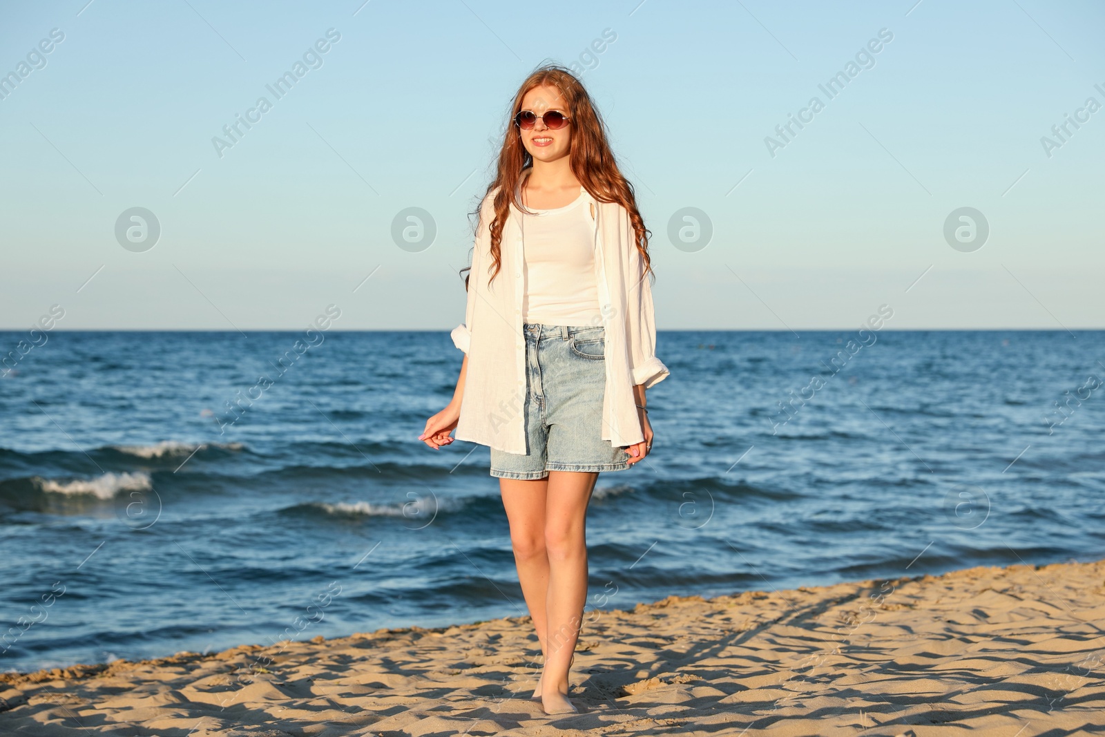 Beautiful teenage girl walking along seashore outdoors Photo of Beautiful teenage girl walking along seashore outdoors