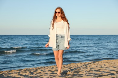 Photo of Beautiful teenage girl walking along seashore outdoors