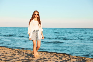 Photo of Beautiful teenage girl walking along seashore outdoors, space for text