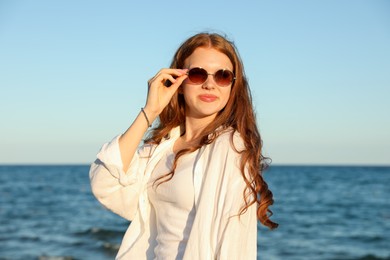 Photo of Beautiful teenage girl in sunglasses near sea