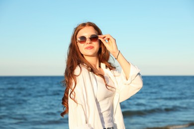 Photo of Beautiful teenage girl in sunglasses near sea