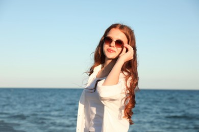 Photo of Beautiful teenage girl in sunglasses near sea