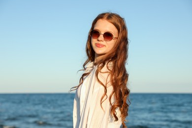 Photo of Beautiful teenage girl in sunglasses near sea
