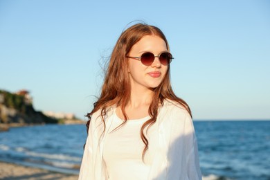 Photo of Beautiful teenage girl in sunglasses near sea